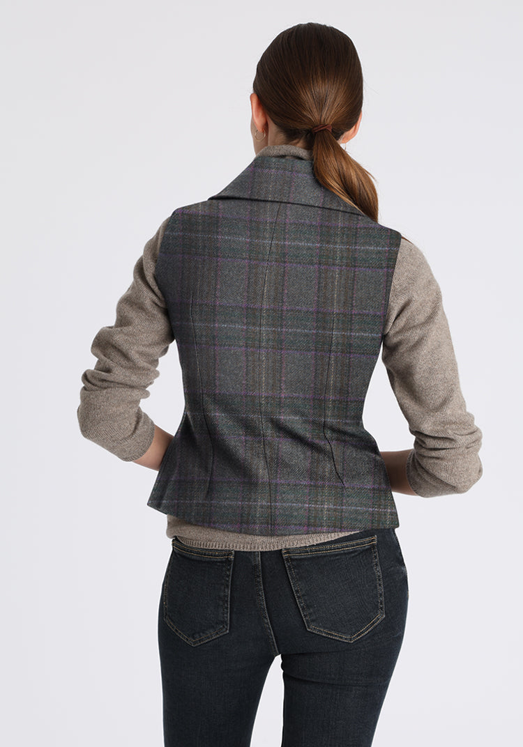 Person wearing a purple gray plaid waistcoat over a gray shirt with a white background