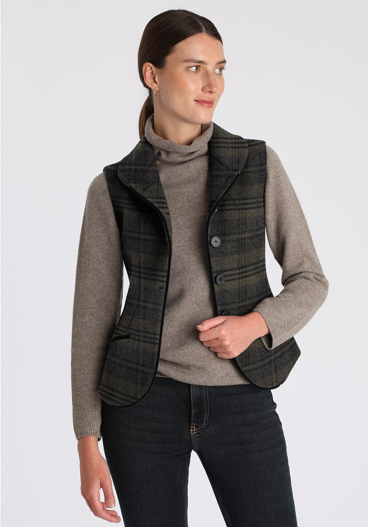 Woman wearing a gray sweater with a plaid waistcoat on a light gray background