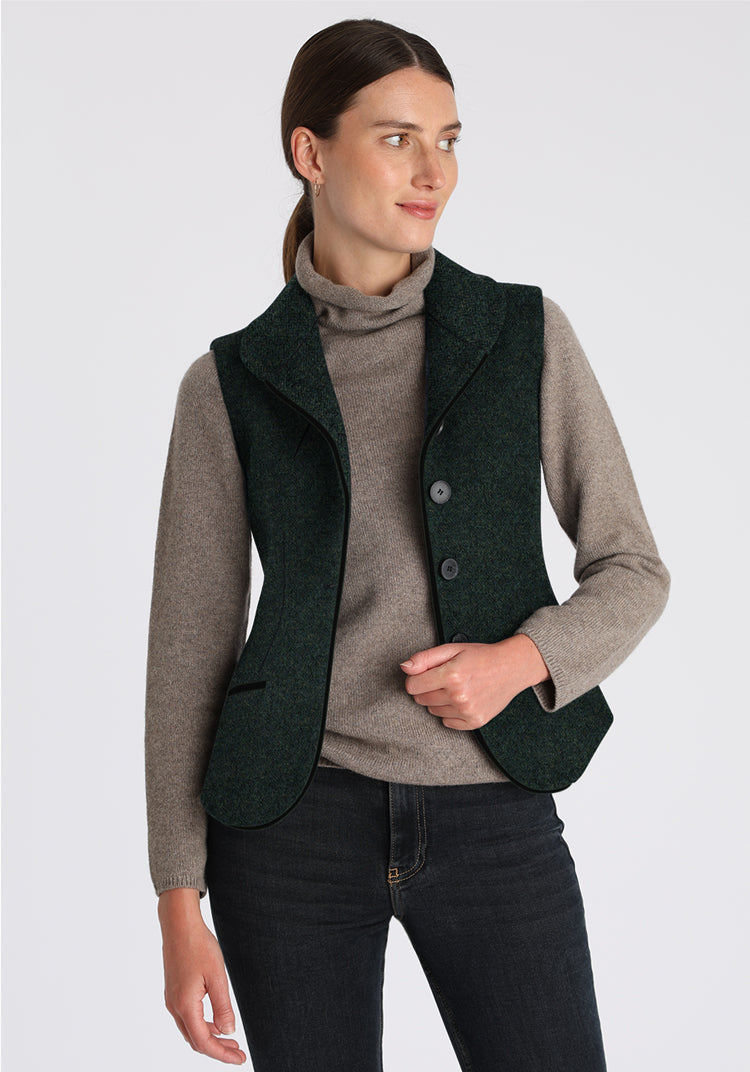 Woman wearing a green waistcoat over a gray sweater on a white background