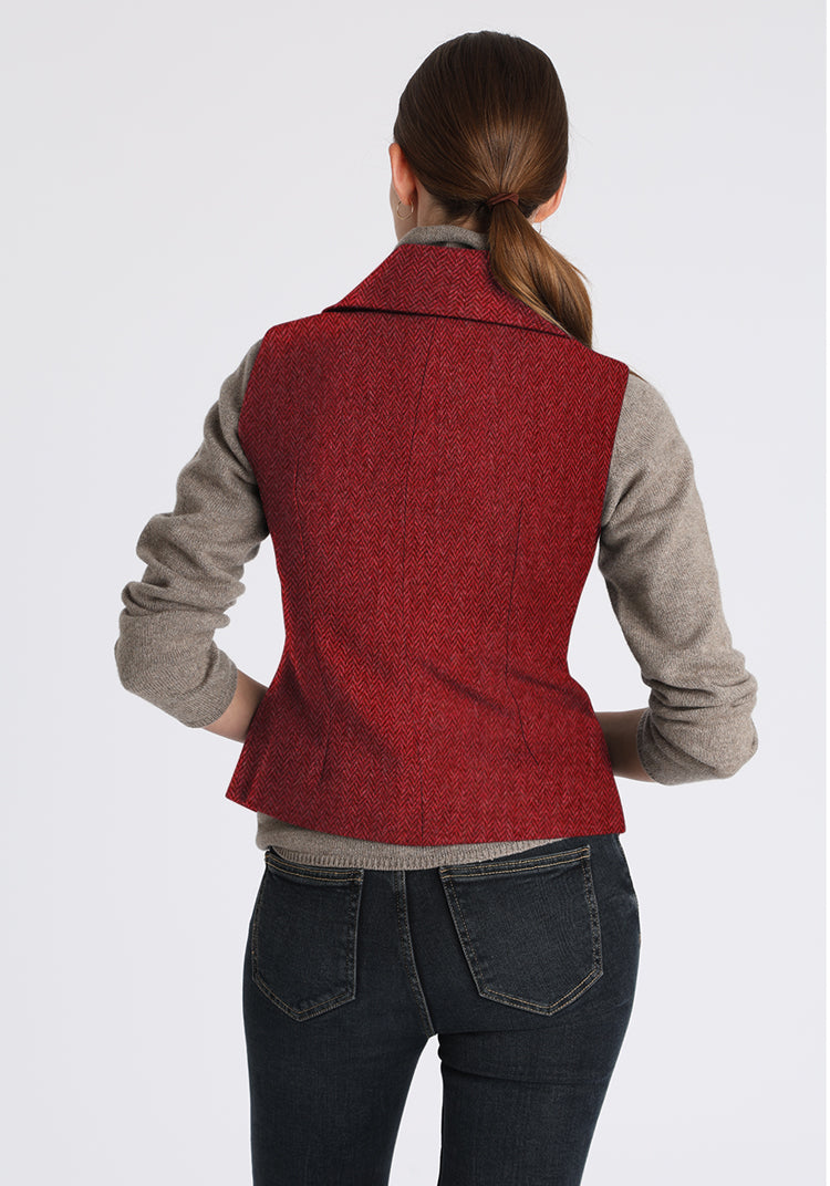 Person wearing a red vest over a gray sweater with a white background