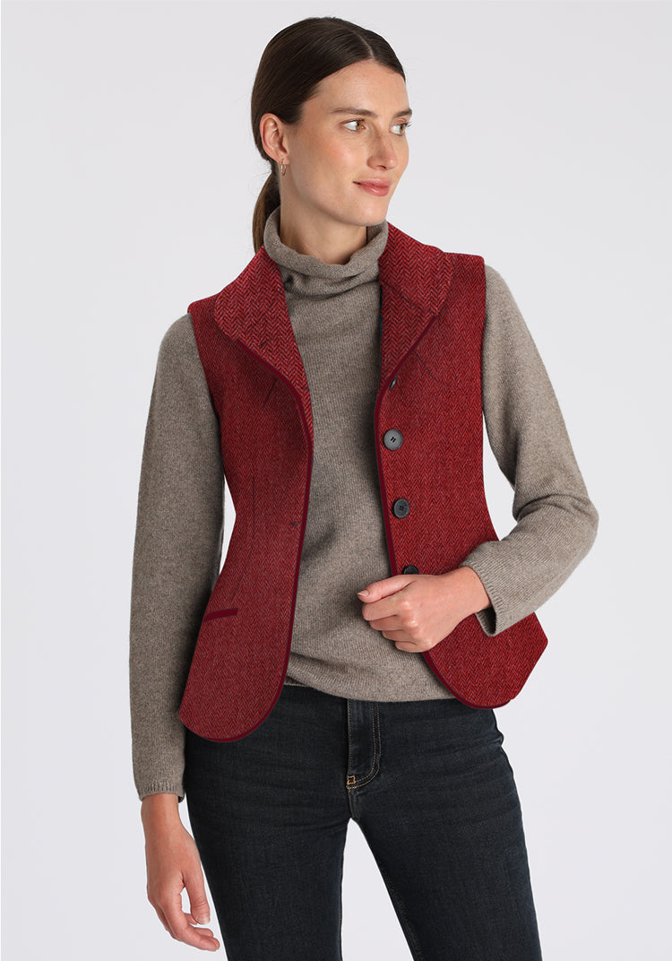 Woman wearing a red vest over a gray sweater on a white background