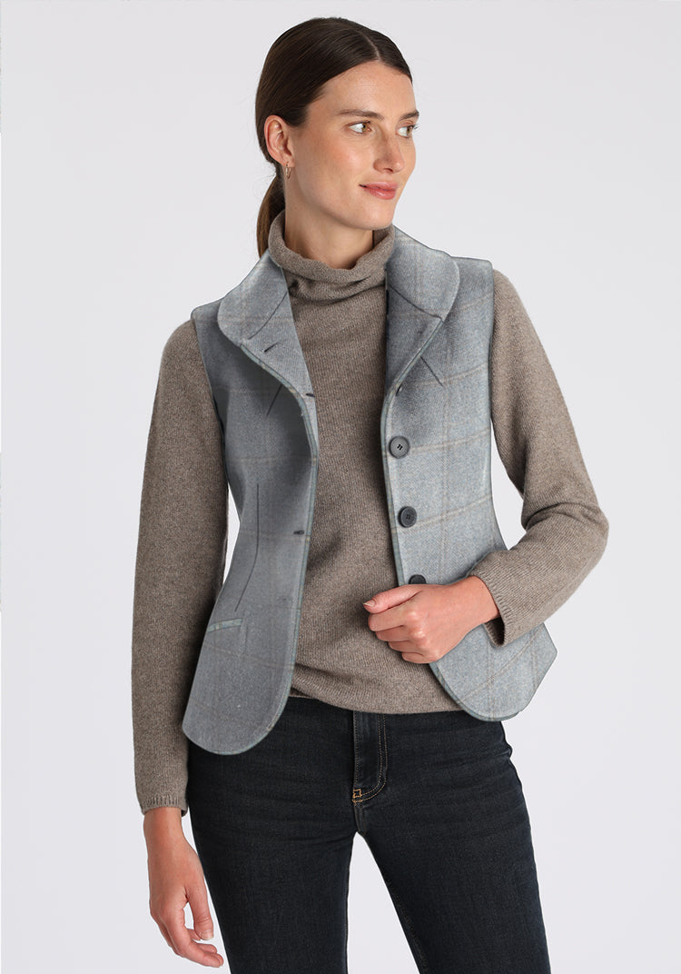 Woman wearing a gray-blue waistcoat over a sweater on a white background