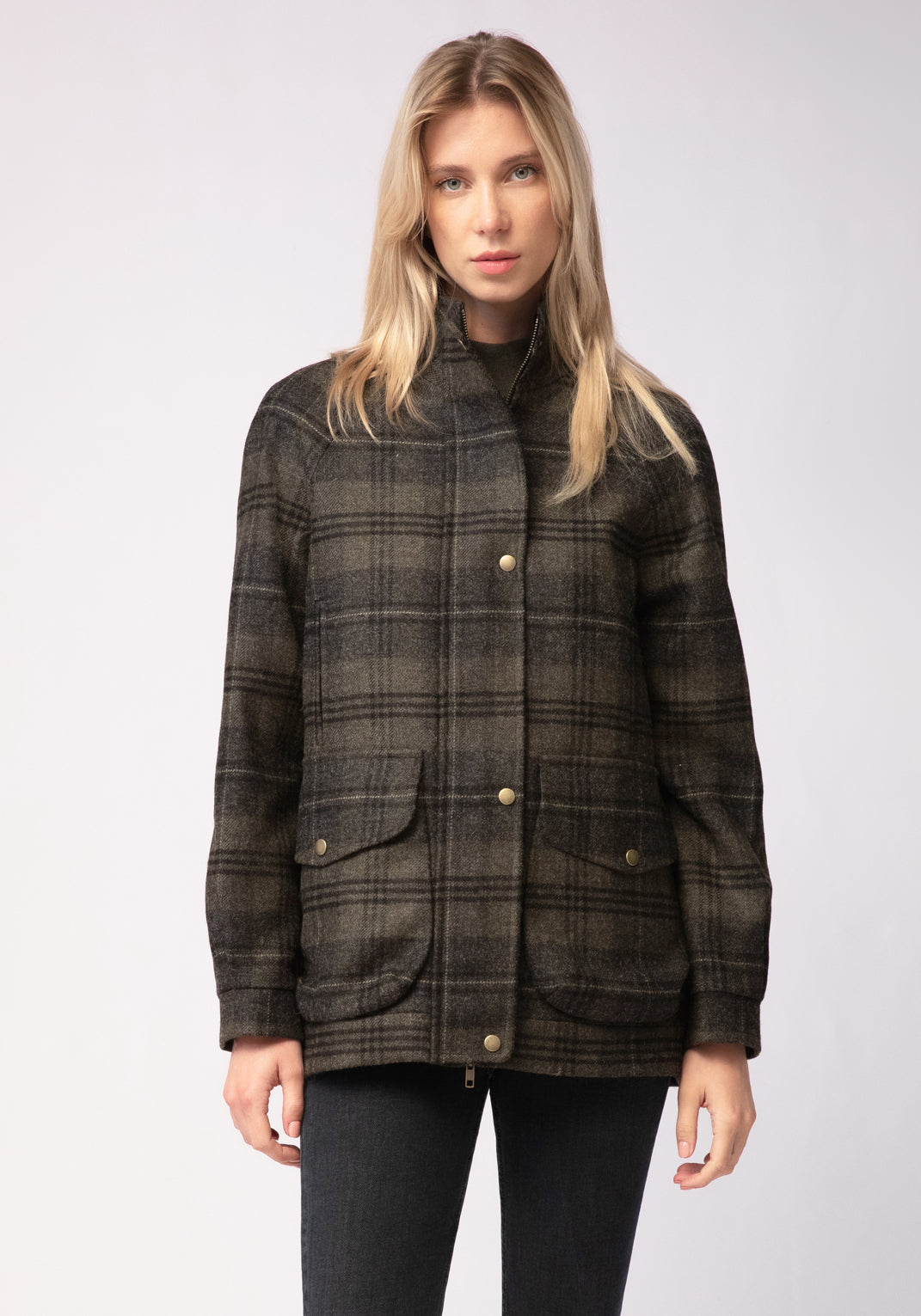 Woman wearing a green and grey plaid jacket on a white background