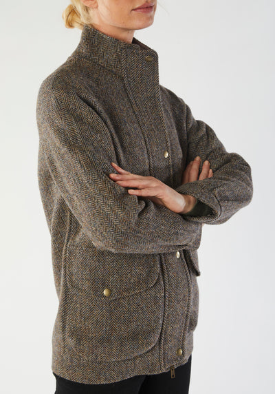 A model wears the Andrea jacket in Harris Tweed, featuring relaxed raglan sleeves, a high neck, generous pockets, and finished with antique brass hardware.