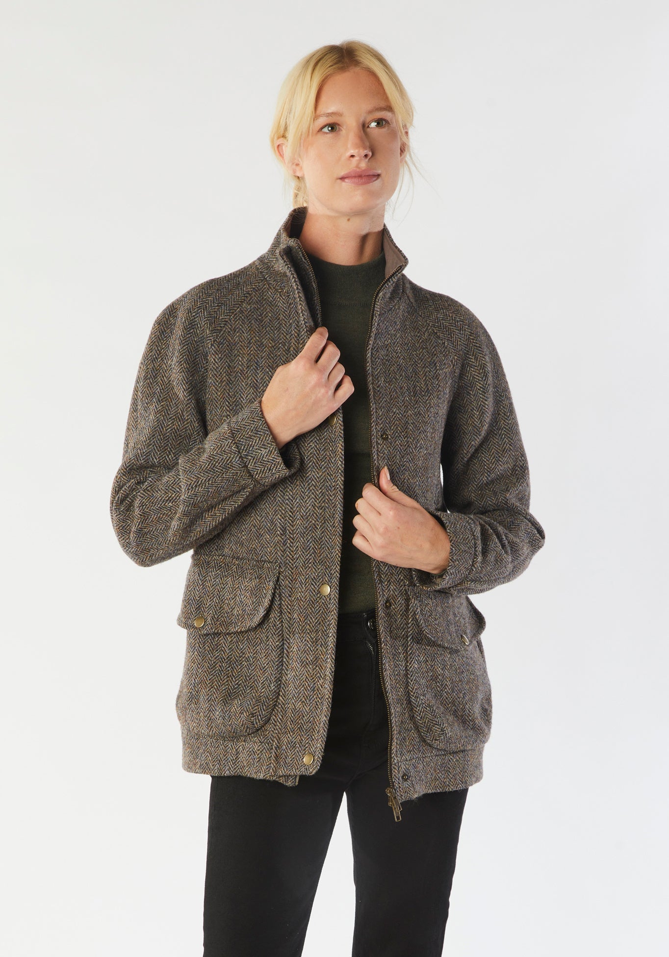 A model wears the Andrea jacket in Harris Tweed, featuring relaxed raglan sleeves, a high neck, generous pockets, and finished with antique brass hardware.