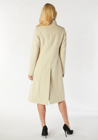 A model wears the Opera coat, a fitted, longline coat made from thick cream merino wool with black contrasting trim.