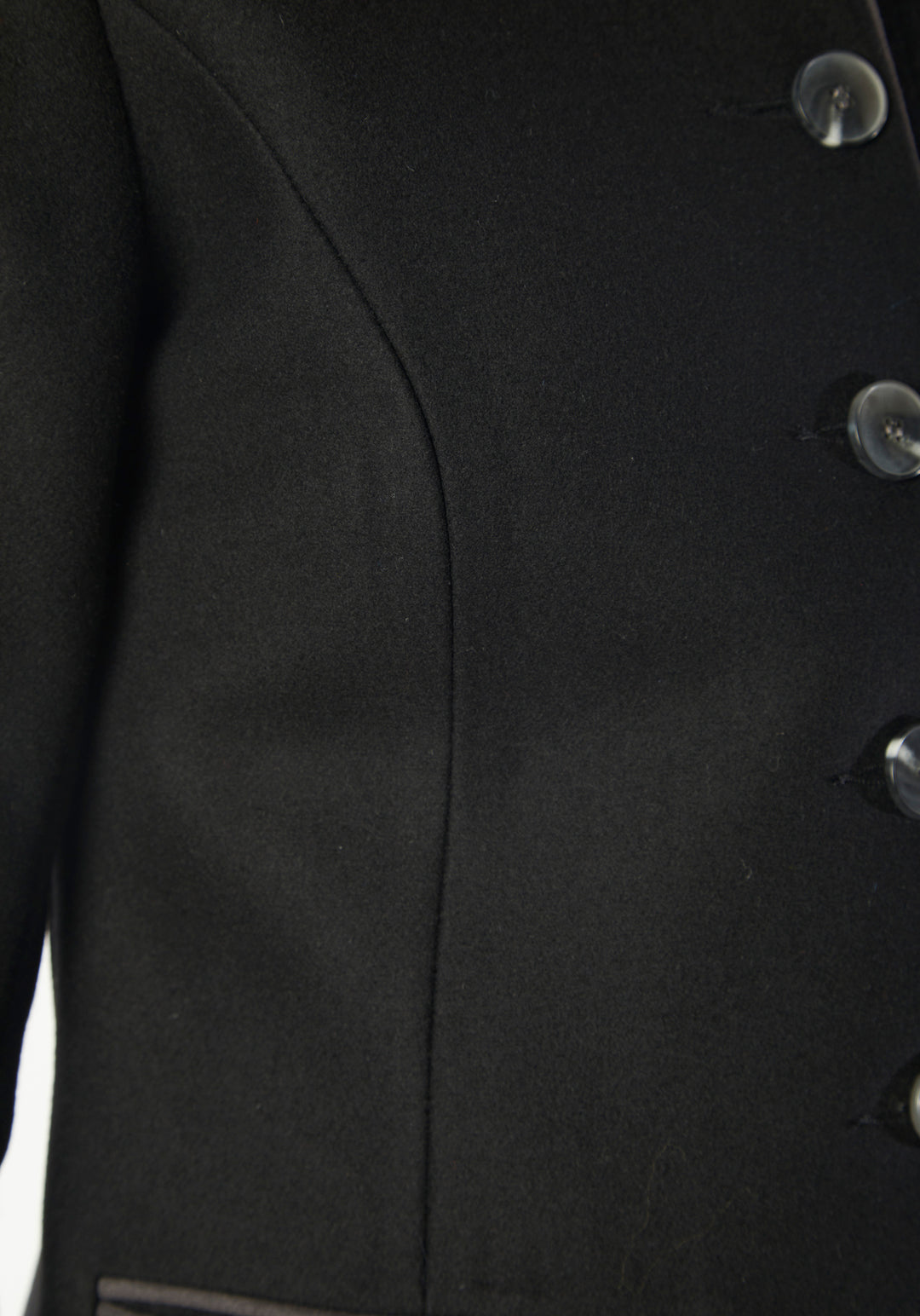 A model wears the Patmos Jacket, a slim-fit design in a black cashmere blend with contrasting grey trim. It features a mandarin collar, front pockets, and deep cuffs with a row of charcoal buttons.