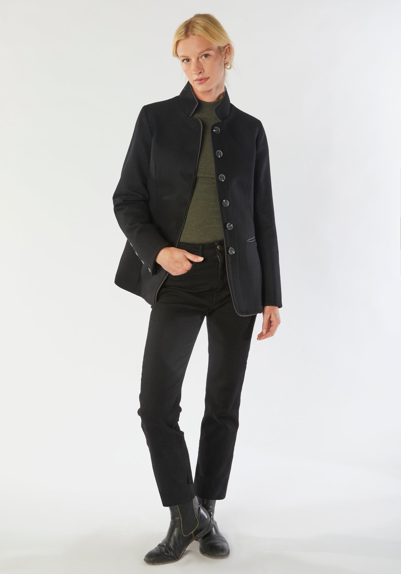 A model wears the Patmos Jacket, a slim-fit design in a black cashmere blend with contrasting grey trim. It features a mandarin collar, front pockets, and deep cuffs with a row of charcoal buttons.