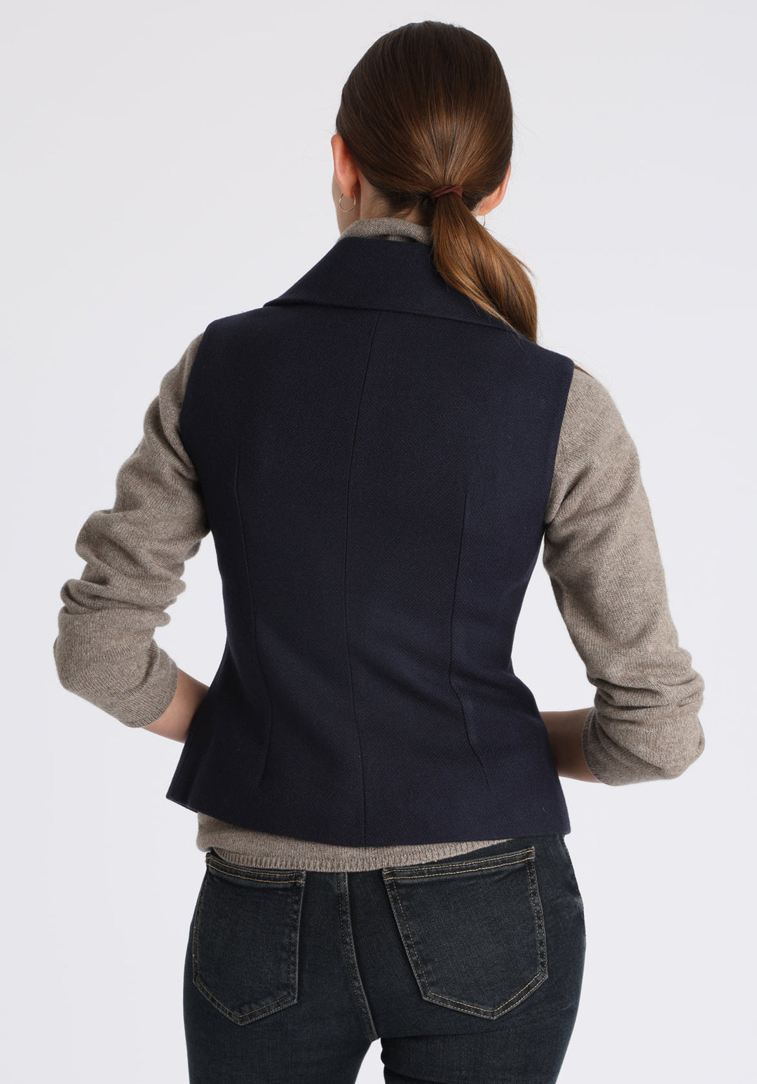 Model wearing the Alexander waistcoat in a textured navy merino wool, a short, fitted style with a shawl collar, suede trim, and curved front hem.