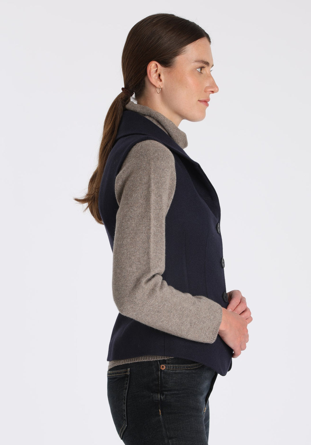 Model wearing the Alexander waistcoat in a textured navy merino wool, a short, fitted style with a shawl collar, suede trim, and curved front hem.