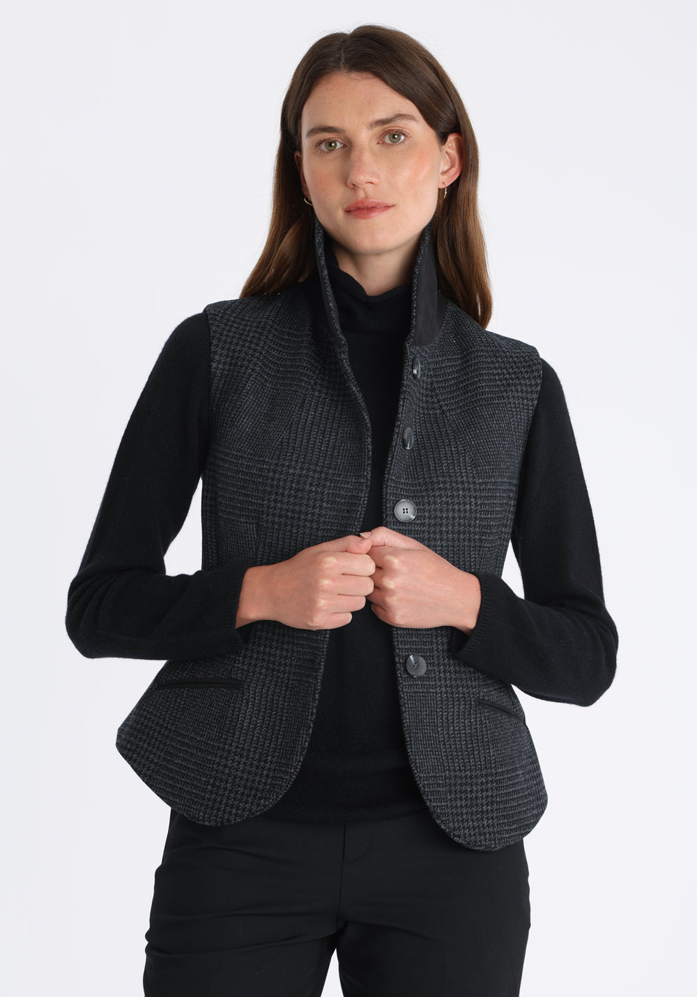 Model wearing the Alexander waistcoat in a black and charcoal grey Prince of Wales check, a short, fitted merino wool style with a shawl collar and curved front hem.