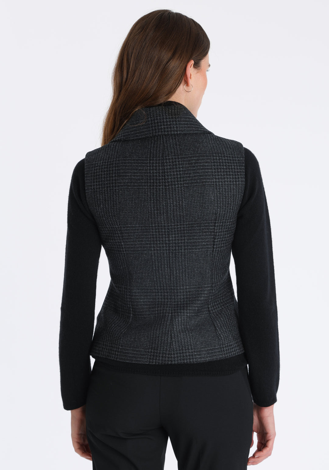 Model wearing the Alexander waistcoat in a black and charcoal grey Prince of Wales check, a short, fitted merino wool style with a shawl collar and curved front hem.