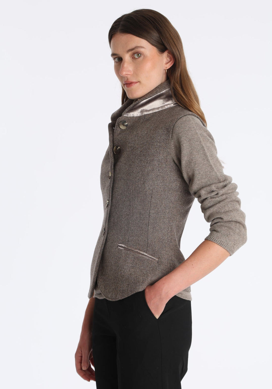 Model wearing the Alexander waistcoat in a cool mallow taupe herringbone lambswool, a short, fitted style with a shawl collar, silk velvet trim, and curved front hem.