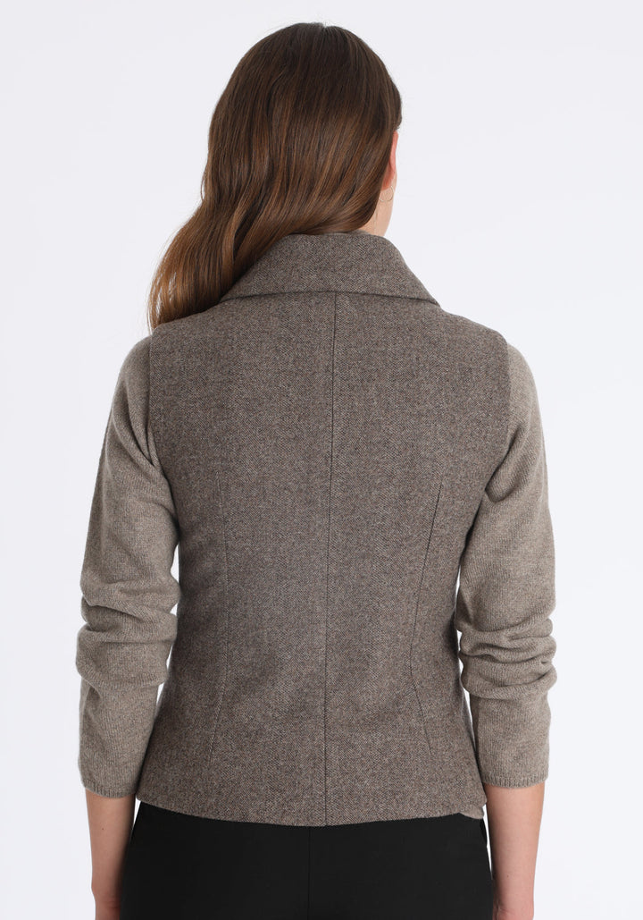 Model wearing the Alexander waistcoat in a cool mallow taupe herringbone lambswool, a short, fitted style with a shawl collar, silk velvet trim, and curved front hem.