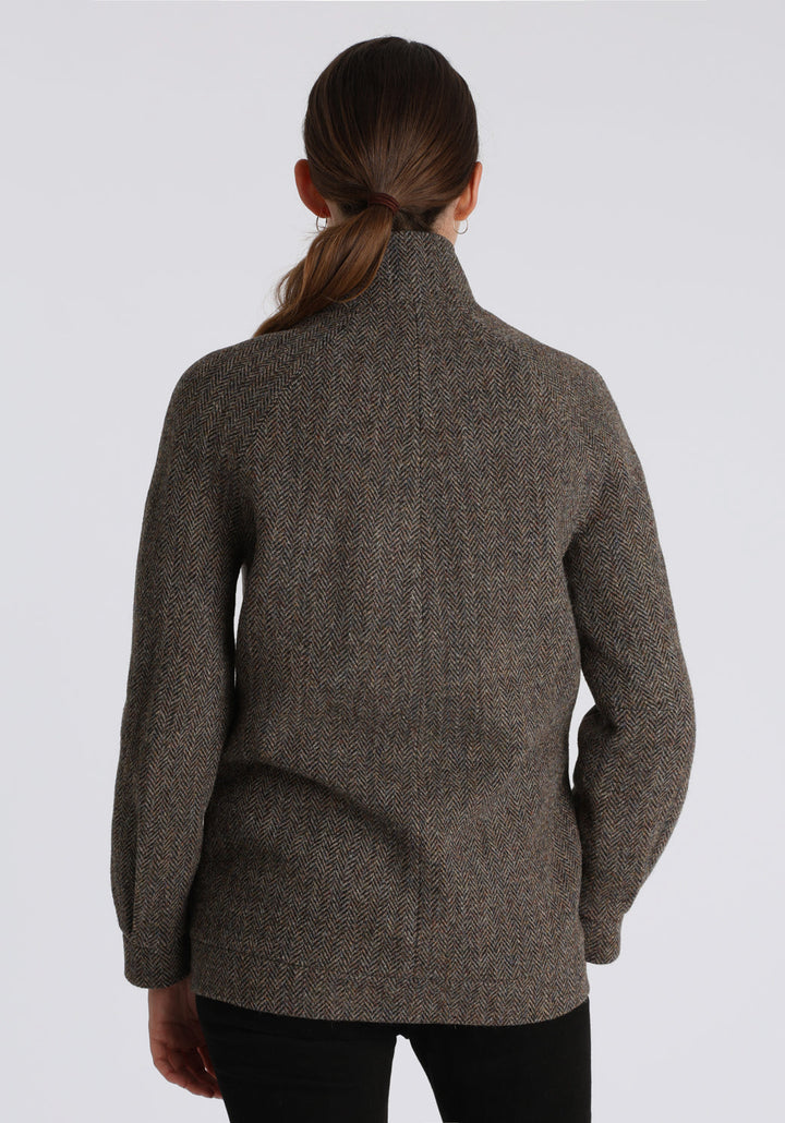 A model wears the Andrea jacket in Harris Tweed, featuring relaxed raglan sleeves, a high neck, generous pockets, and finished with antique brass hardware.