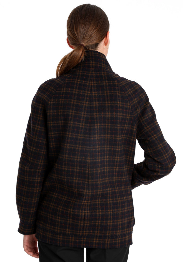 Model wearing the Andrea jacket in navy and rust thick merino wool, a heritage-inspired style with relaxed raglan sleeves, a high neck, and generous pockets, finished with antique brass hardware.
