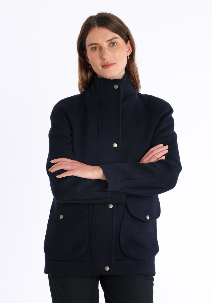 Model wearing the Andrea jacket in navy and rust thick merino wool, a heritage-inspired style with relaxed raglan sleeves, a high neck, and generous pockets, finished with antique brass hardware.
