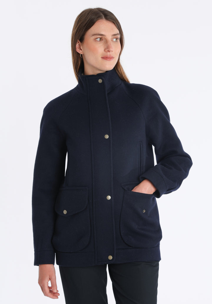 Model wearing the Andrea jacket in navy and rust thick merino wool, a heritage-inspired style with relaxed raglan sleeves, a high neck, and generous pockets, finished with antique brass hardware.