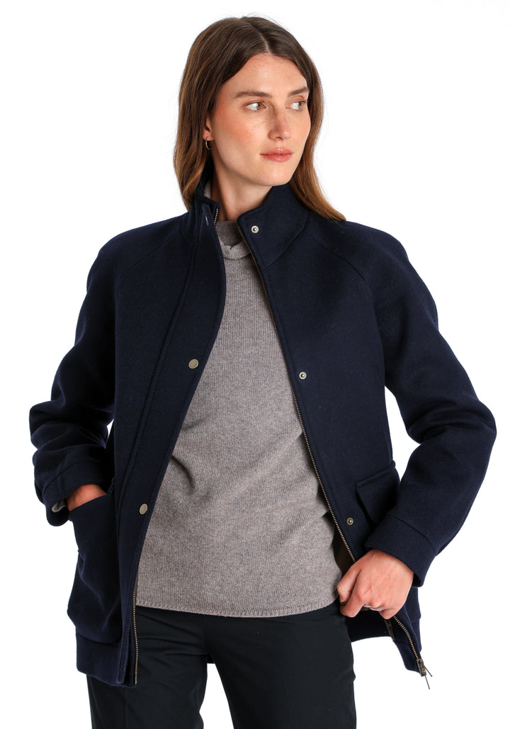 Model wearing the Andrea jacket in navy and rust thick merino wool, a heritage-inspired style with relaxed raglan sleeves, a high neck, and generous pockets, finished with antique brass hardware.