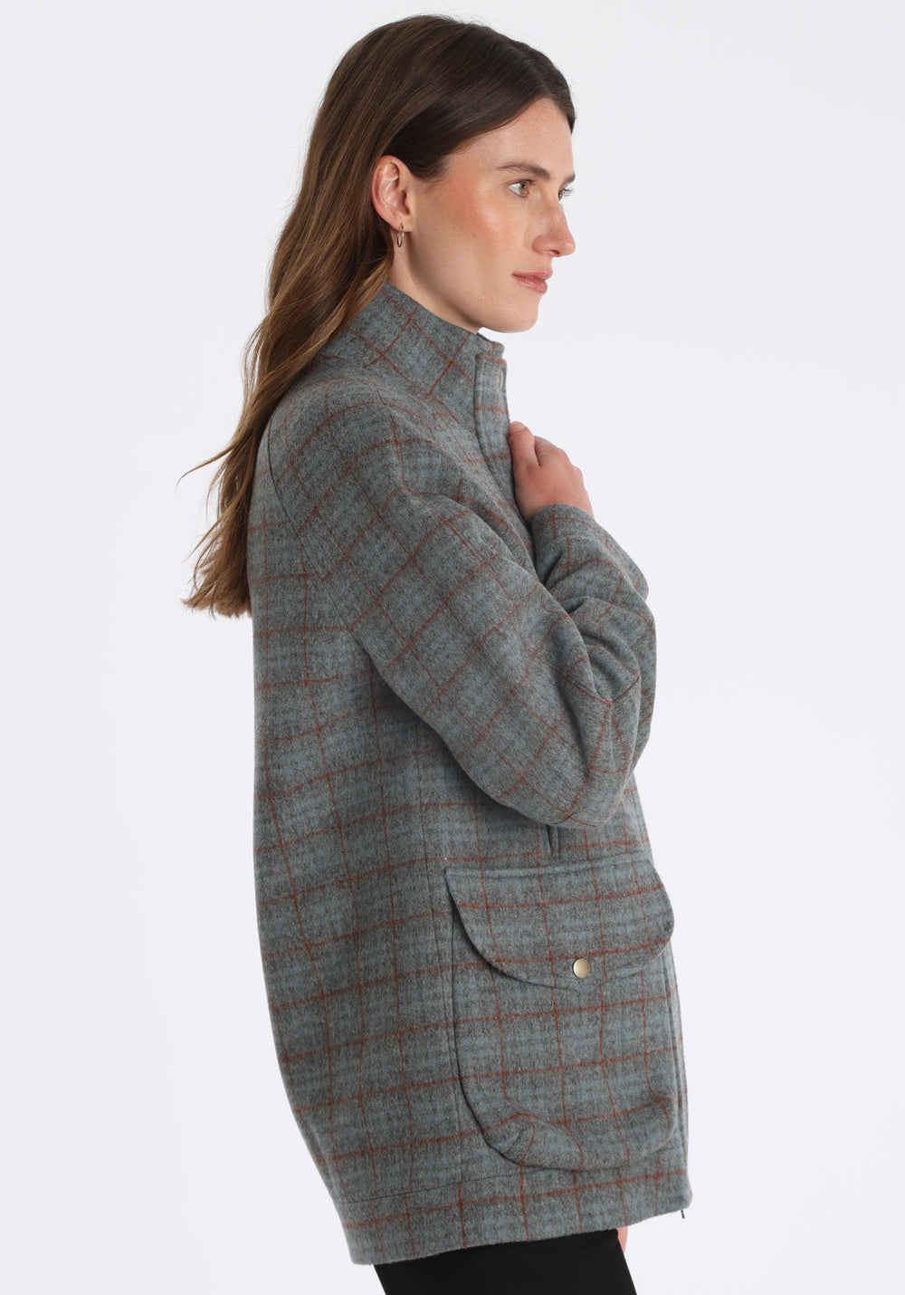 Model wearing the Andrea jacket in silver blue and rust check thick merino wool, a heritage-inspired style with relaxed raglan sleeves, a high neck, and generous pockets, finished with silk velvet trim.