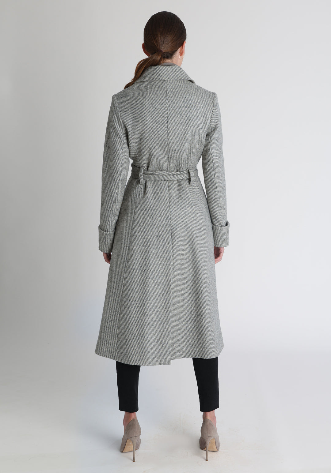 Model wearing the Belted coat in slate blue and cream twill lambswool, a long tailored style with a matching belt, turn-back cuffs, and a deep back vent for ease of movement.
