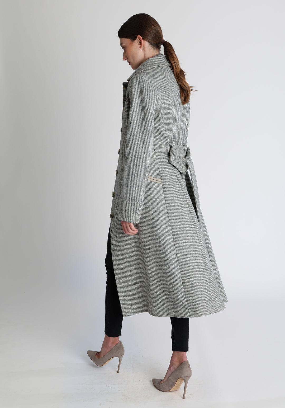 Model wearing the Belted coat in slate blue and cream twill lambswool, a long tailored style with a matching belt, turn-back cuffs, and a deep back vent for ease of movement.