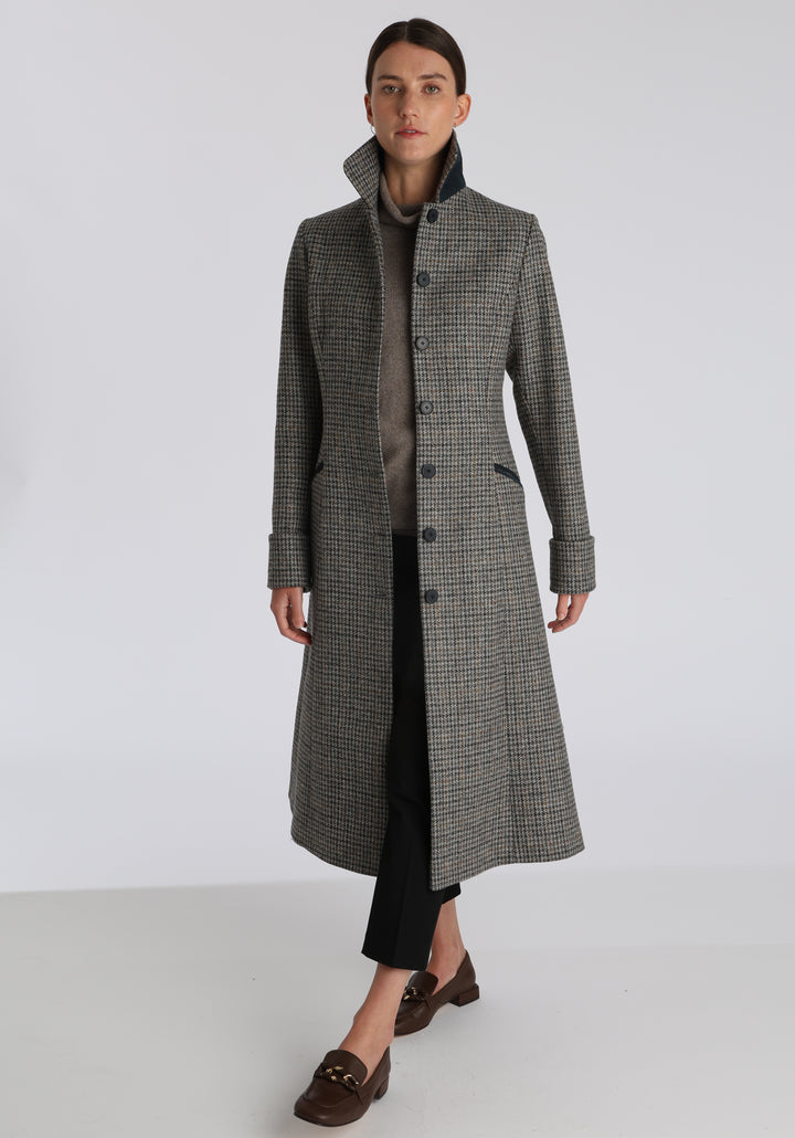 Model wearing the Belted coat in stone grey and ochre dogtooth check wool, a long tailored style with a matching belt, turn-back cuffs, and a deep back vent for ease of movement.