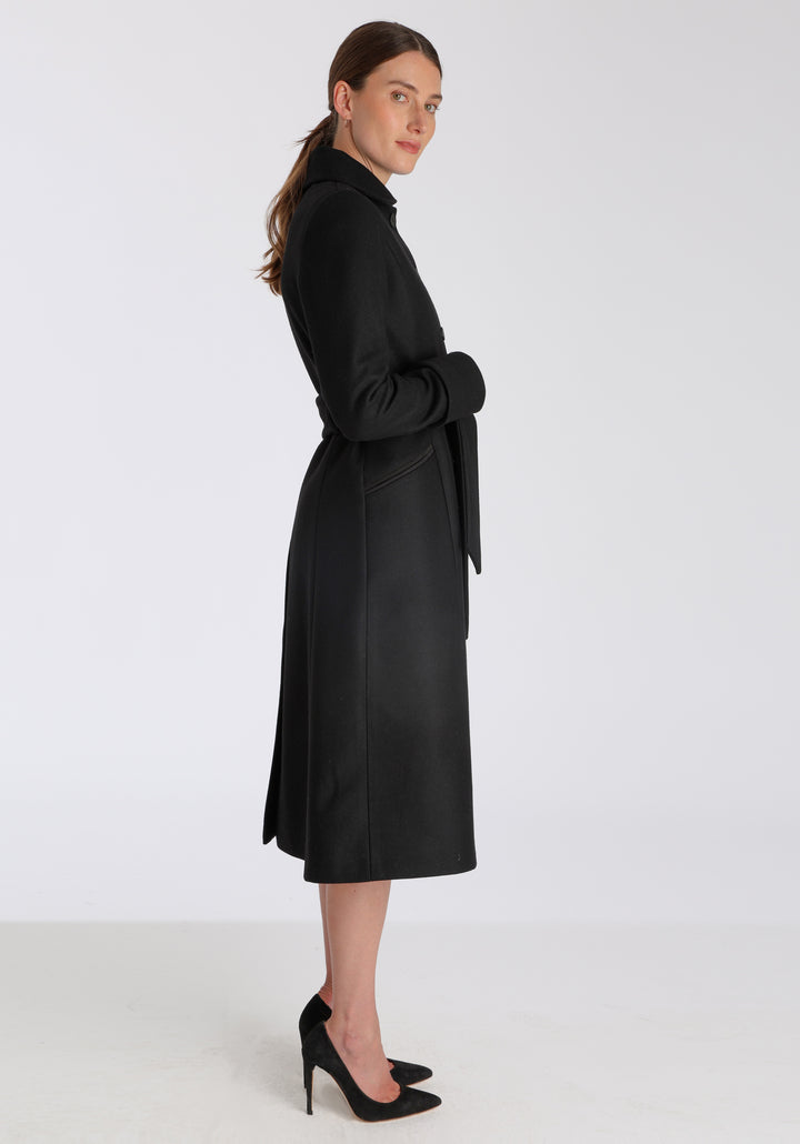 Model wearing the Belted coat in black cashmere blend, a long tailored style with a matching belt, turn-back cuffs, and a deep back vent for ease of movement.