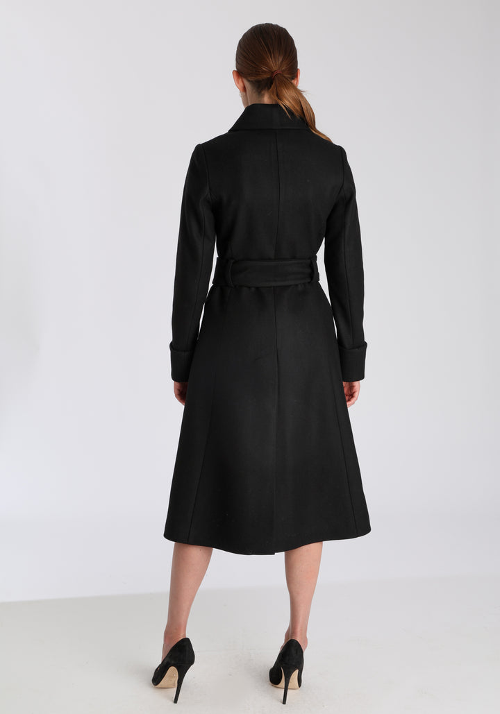 Model wearing the Belted coat in black cashmere blend, a long tailored style with a matching belt, turn-back cuffs, and a deep back vent for ease of movement.