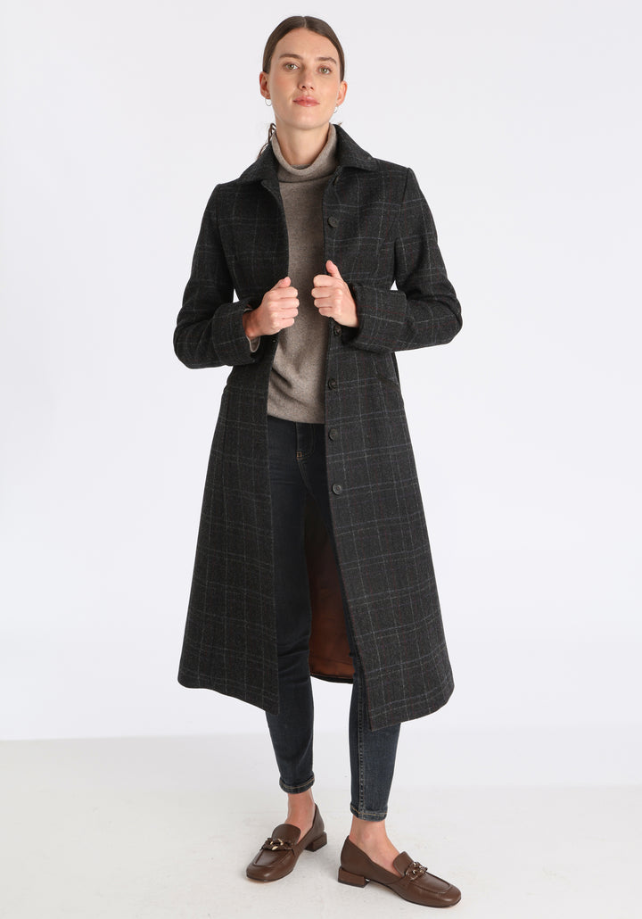 Model wearing the Belted coat in black with faint overcheck, a long tailored style with a matching belt, turn-back cuffs, and a deep back vent for ease of movement.