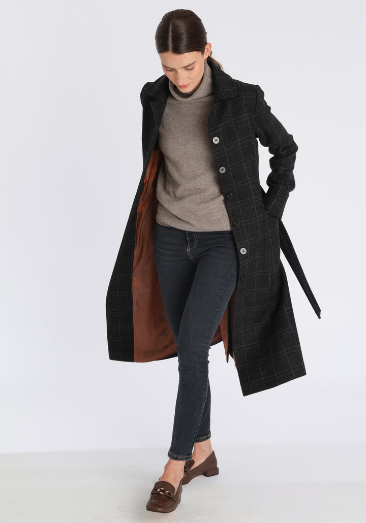 Model wearing the Belted coat in black with faint overcheck, a long tailored style with a matching belt, turn-back cuffs, and a deep back vent for ease of movement.