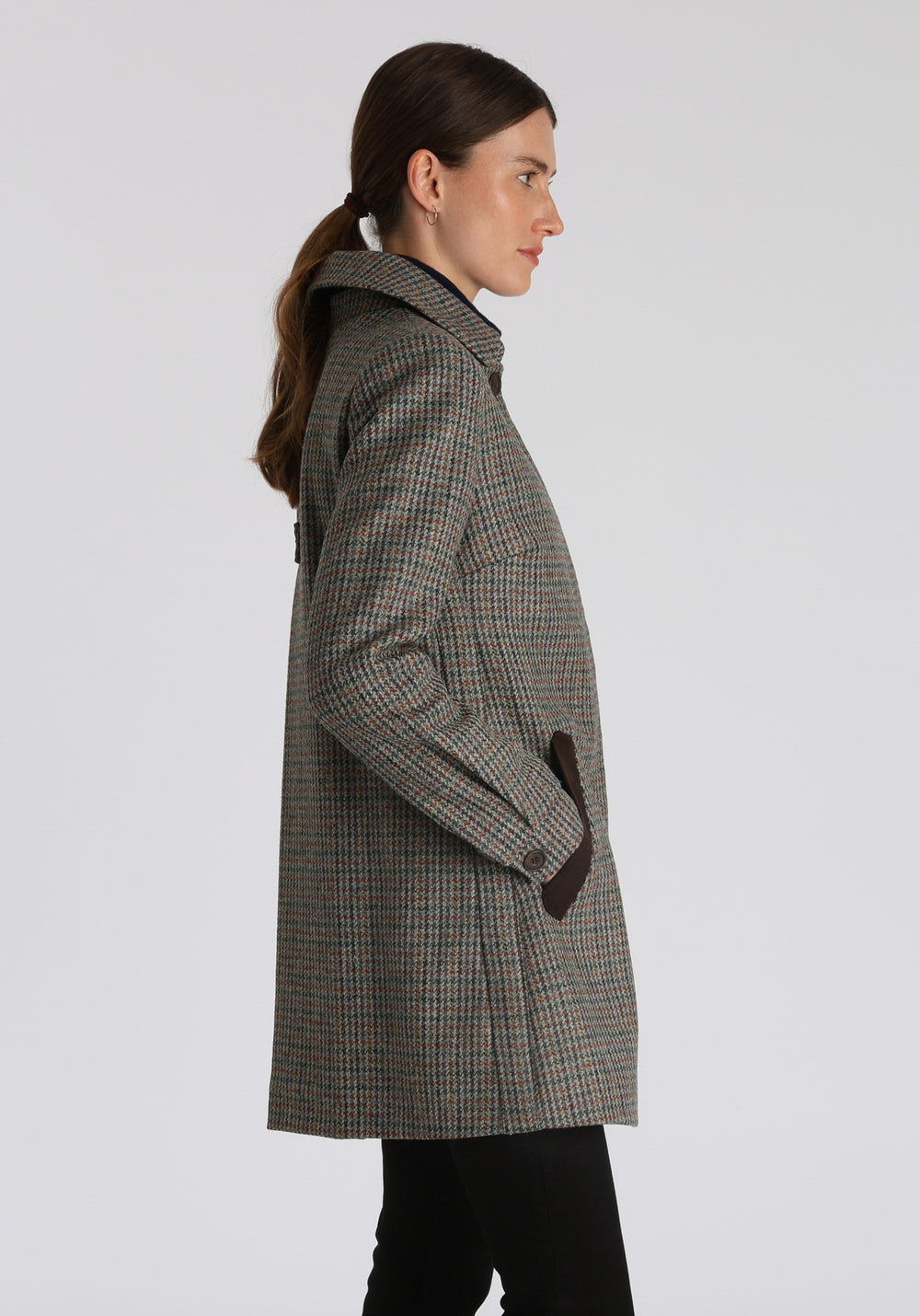 Model wearing the Cape coat in autumnal cinder dogtooth check, a short, structured style with a generous collar, buttoned cuffs, and a deep back pleat that creates a subtle cape-like shape.
