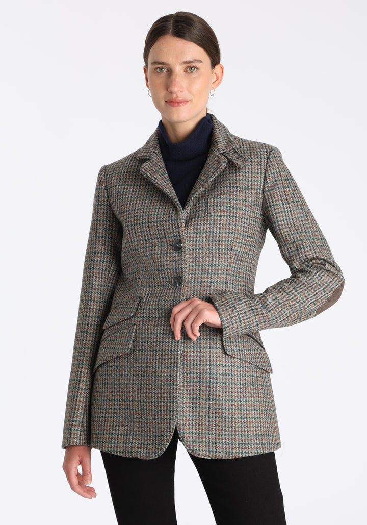 Model wearing the Cass jacket in autumnal cinder dogtooth wool check with silk velvet trim, a longline, relaxed boyfriend-style jacket with welt pockets, and buttoned collar tab inspired by equestrian tailoring.