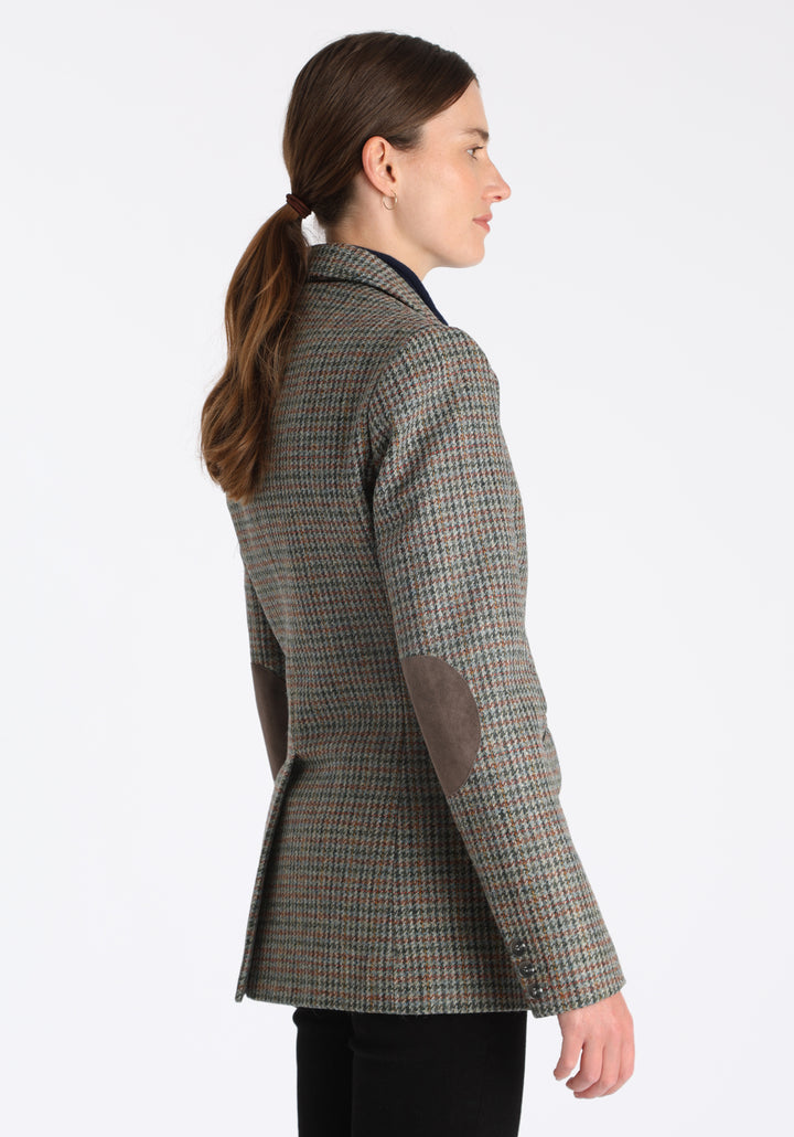 Model wearing the Cass jacket in autumnal cinder dogtooth wool check with silk velvet trim, a longline, relaxed boyfriend-style jacket with welt pockets, and buttoned collar tab inspired by equestrian tailoring.