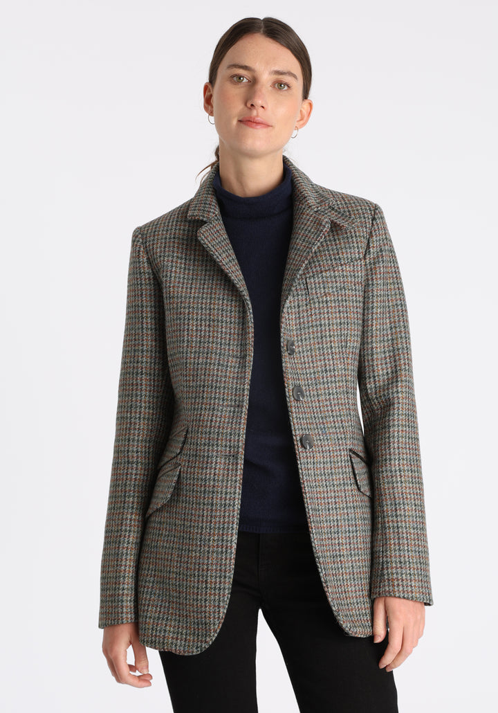 Model wearing the Cass jacket in autumnal cinder dogtooth wool check with silk velvet trim, a longline, relaxed boyfriend-style jacket with welt pockets, and buttoned collar tab inspired by equestrian tailoring.