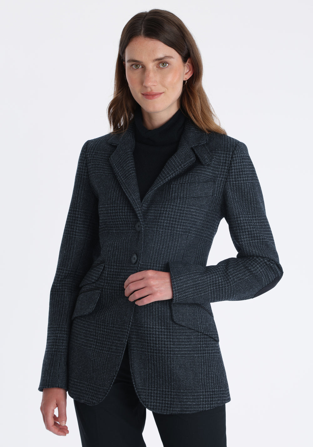 Model wearing the Cass jacket in black and charcoal grey Prince of Wales wool check with suede trim, a longline, relaxed boyfriend-style jacket with welt pockets, and buttoned collar tab inspired by equestrian tailoring.