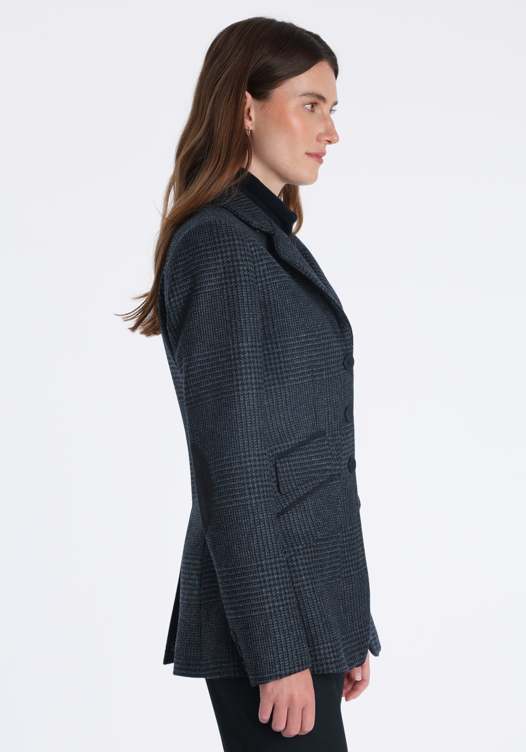 Model wearing the Cass jacket in black and charcoal grey Prince of Wales wool check with suede trim, a longline, relaxed boyfriend-style jacket with welt pockets, and buttoned collar tab inspired by equestrian tailoring.