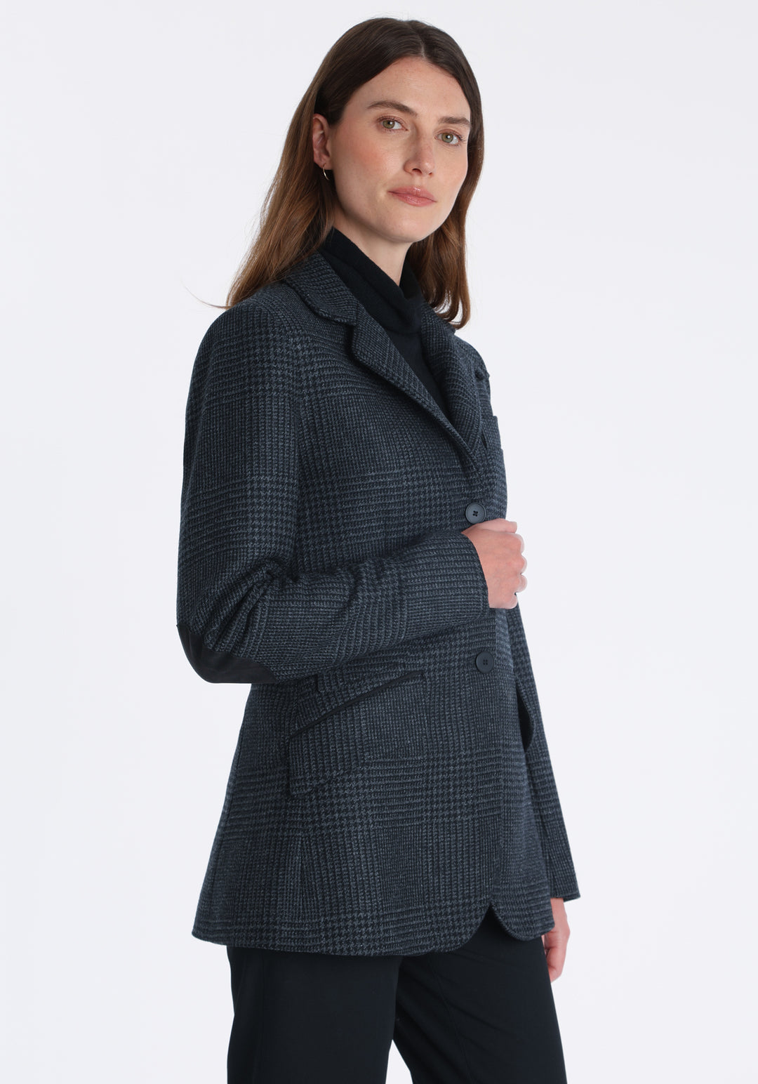 Model wearing the Cass jacket in black and charcoal grey Prince of Wales wool check with suede trim, a longline, relaxed boyfriend-style jacket with welt pockets, and buttoned collar tab inspired by equestrian tailoring.