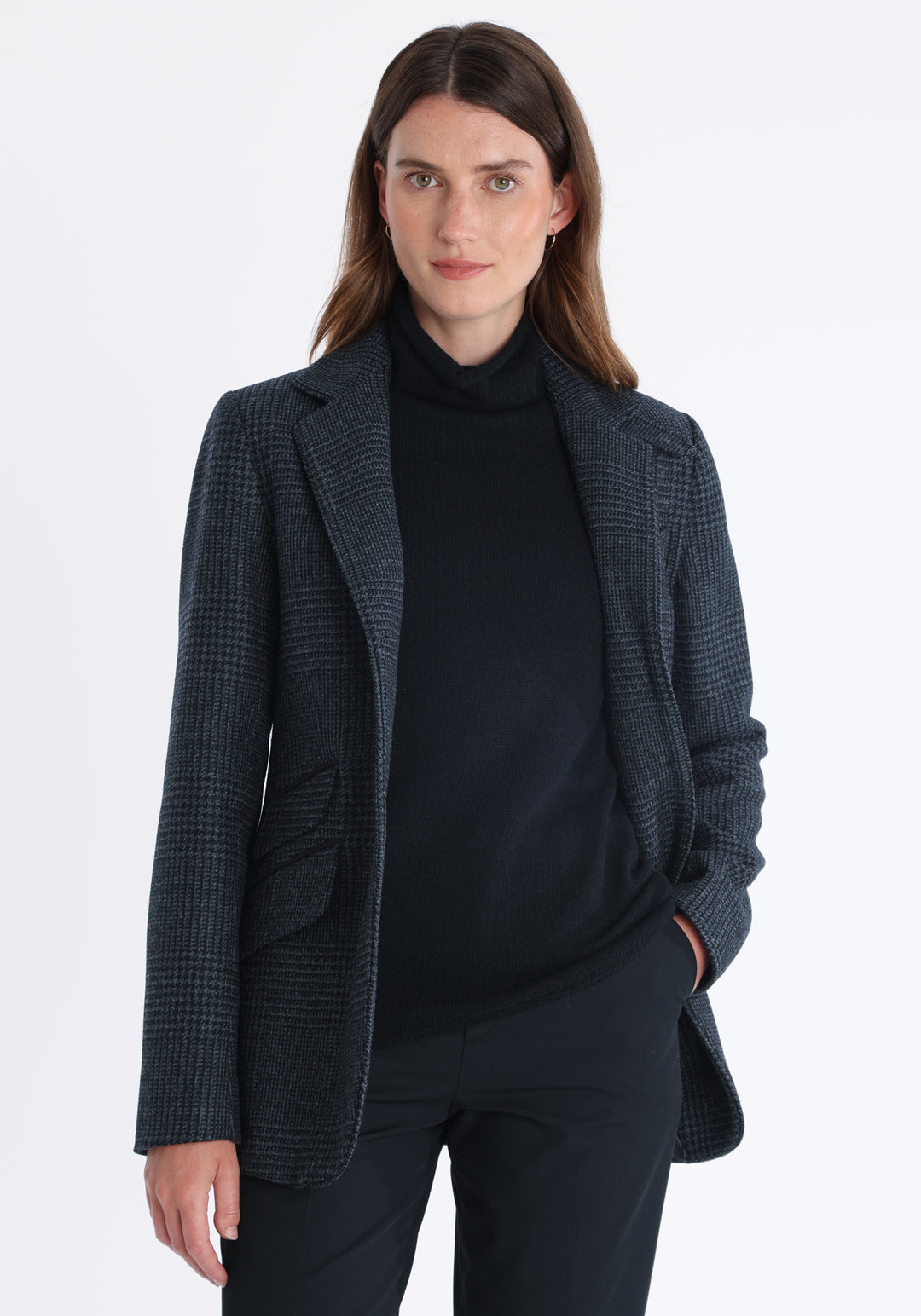 Model wearing the Cass jacket in black and charcoal grey Prince of Wales wool check with suede trim, a longline, relaxed boyfriend-style jacket with welt pockets, and buttoned collar tab inspired by equestrian tailoring.