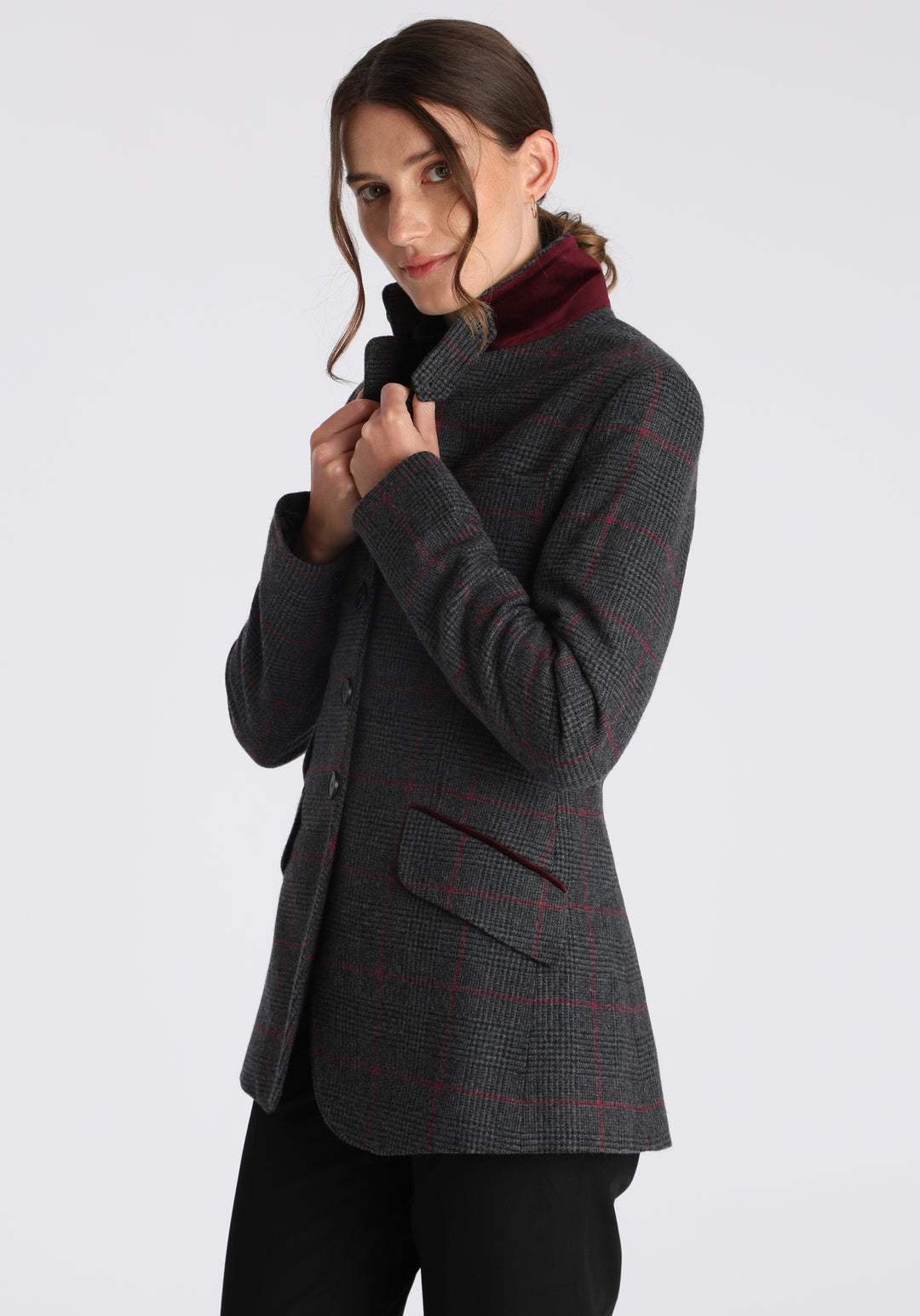 Model wearing the Cass jacket in grey a fuschia winterberry wool cashmere check with cotton velvet trim, a longline, relaxed boyfriend-style jacket with welt pockets, and buttoned collar tab inspired by equestrian tailoring.