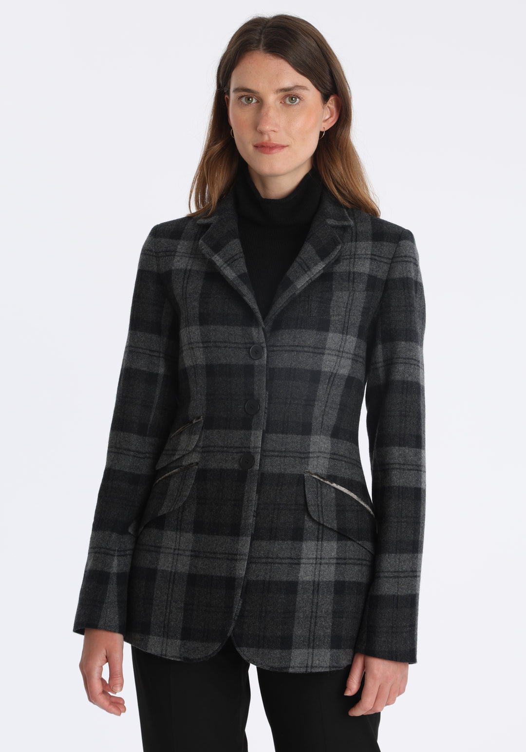 Model wearing the Cass jacket in black and grey tartan cashmere blend with silk velvet trim, a longline, relaxed boyfriend-style jacket with welt pockets, and buttoned collar tab inspired by equestrian tailoring.
