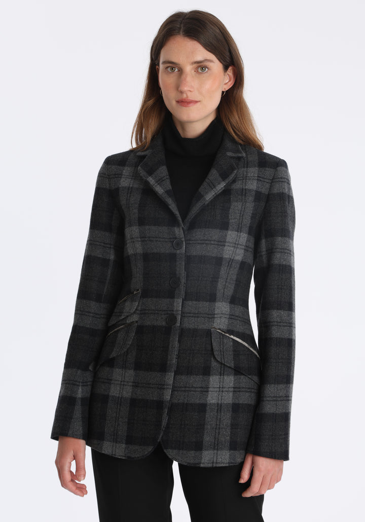Model wearing the Cass jacket in black and grey tartan cashmere blend with silk velvet trim, a longline, relaxed boyfriend-style jacket with welt pockets, and buttoned collar tab inspired by equestrian tailoring.