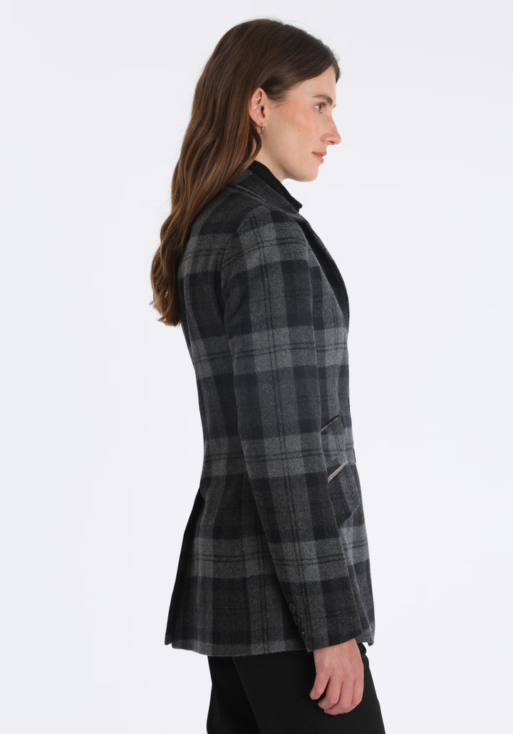 Model wearing the Cass jacket in black and grey tartan cashmere blend with silk velvet trim, a longline, relaxed boyfriend-style jacket with welt pockets, and buttoned collar tab inspired by equestrian tailoring.