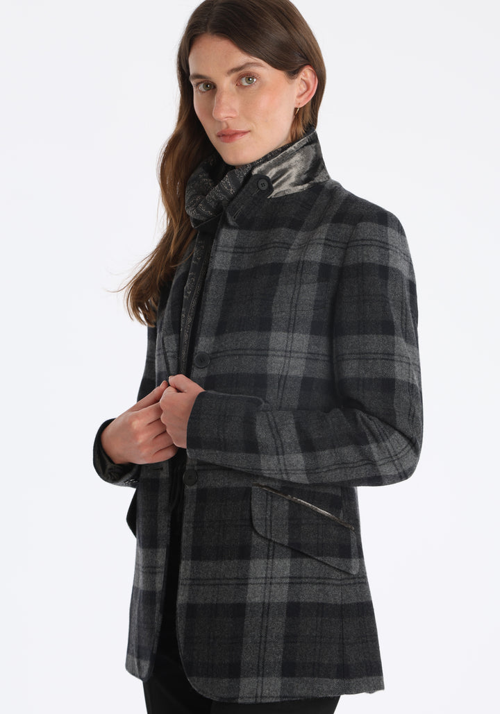 Model wearing the Cass jacket in black and grey tartan cashmere blend with silk velvet trim, a longline, relaxed boyfriend-style jacket with welt pockets, and buttoned collar tab inspired by equestrian tailoring.