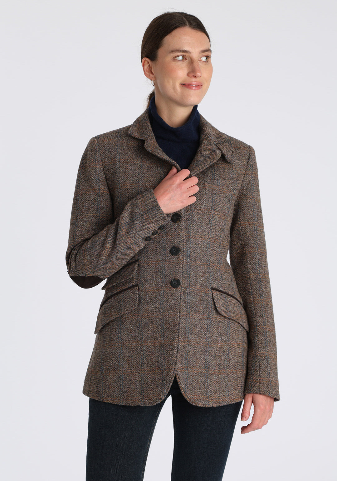 Model wearing the Cass jacket in clay check Harris Tweed with suede trim, a longline, relaxed boyfriend-style jacket with welt pockets, and buttoned collar tab inspired by equestrian tailoring.