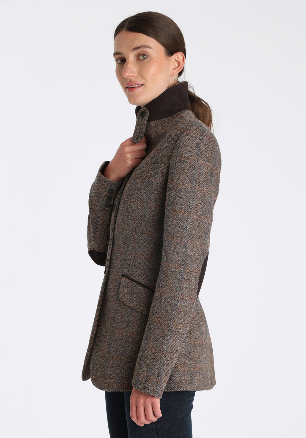 Model wearing the Cass jacket in clay check Harris Tweed with suede trim, a longline, relaxed boyfriend-style jacket with welt pockets, and buttoned collar tab inspired by equestrian tailoring.