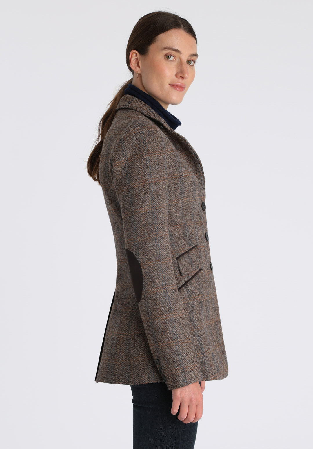 Model wearing the Cass jacket in clay check Harris Tweed with suede trim, a longline, relaxed boyfriend-style jacket with welt pockets, and buttoned collar tab inspired by equestrian tailoring.