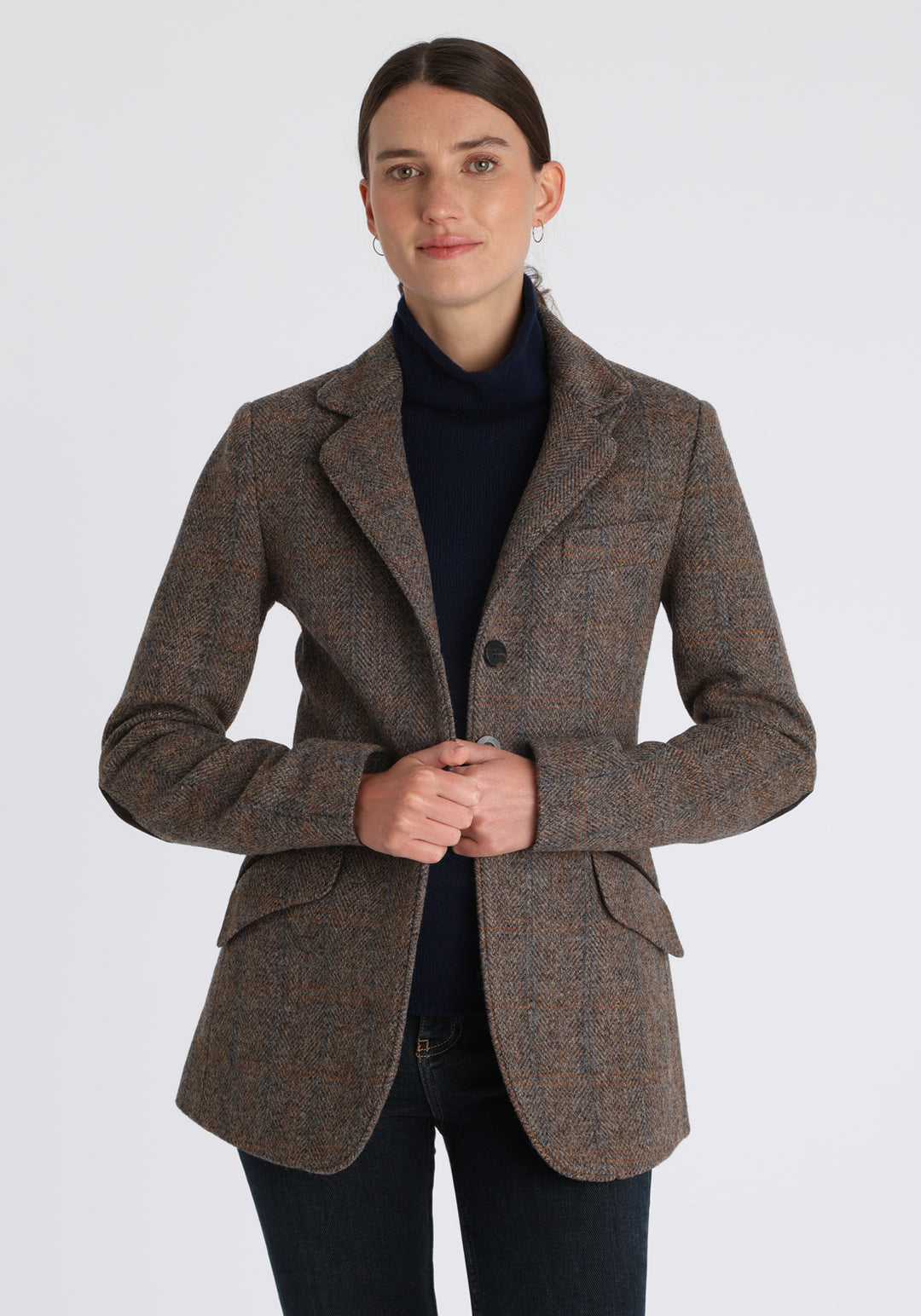 Model wearing the Cass jacket in clay check Harris Tweed with suede trim, a longline, relaxed boyfriend-style jacket with welt pockets, and buttoned collar tab inspired by equestrian tailoring.