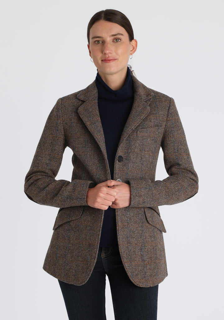 Model wearing the Cass jacket in clay check Harris Tweed with suede trim, a longline, relaxed boyfriend-style jacket with welt pockets, and buttoned collar tab inspired by equestrian tailoring.