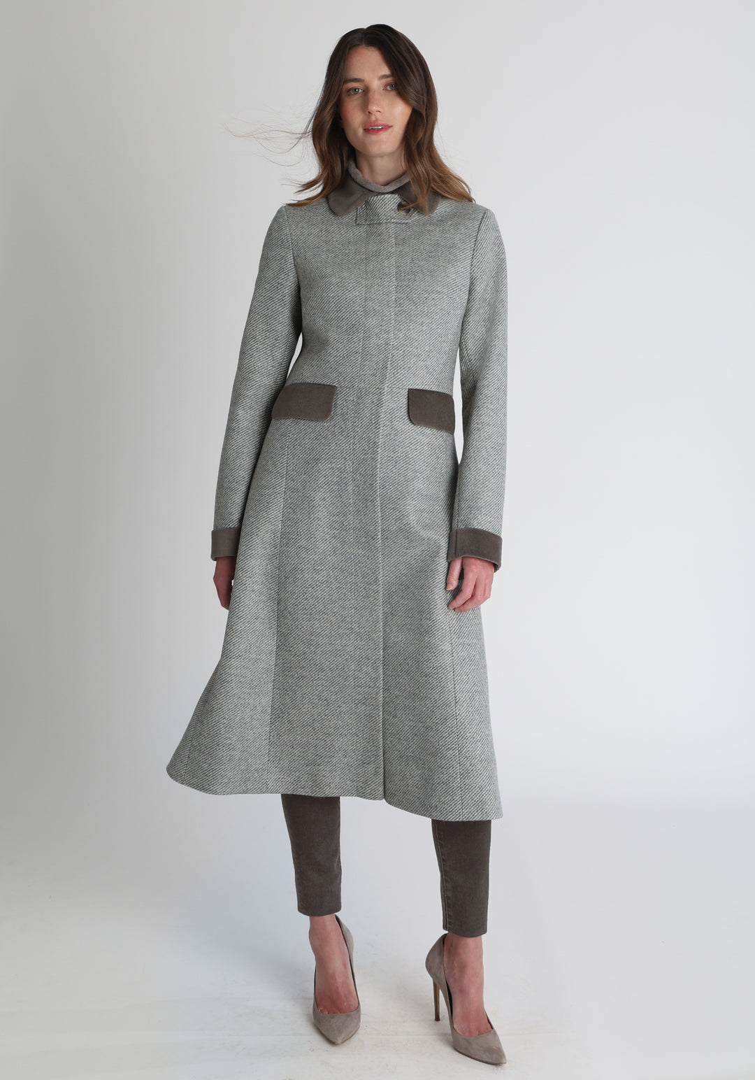Model wearing the Contrast coat in slate blue and cream twill lambswool with cotton velvet detailing on the collar, cuffs, back belt, and pocket flaps, a longline occasion wear style with a timeless silhouette.